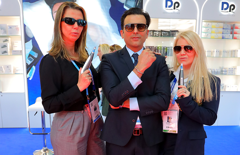 Dr Bilal Malik with DermapenWorld team holding devices at AMWC Monaco booth
