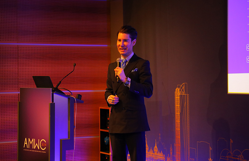 Dr Bilal Malik speaking on stage at AMWC Monaco aesthetic conference